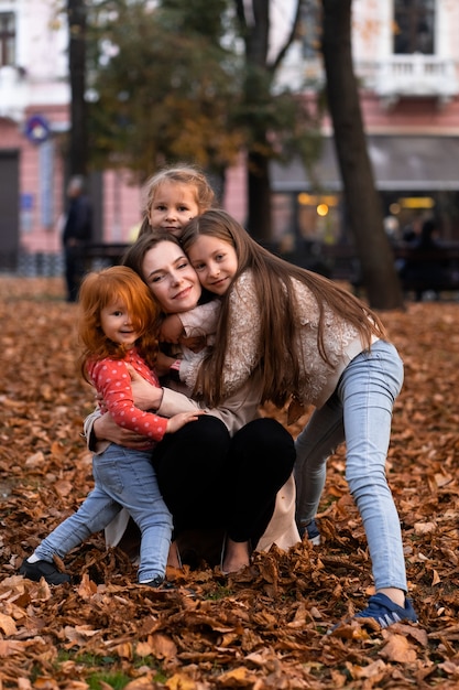 Szczęśliwa rodzina. matka wielu dzieci i trzech córek dziewczynka razem, przytulanie, radosny śmiech i zabawa podczas odpoczynku w parku podczas jesiennych wakacji. Rodzinny styl życia na świeżym powietrzu.