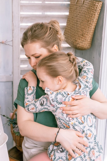 Zdjęcie szczęśliwa rodzina matka z małą córeczką, która bawi się na przedmieściach wiejskie życie domowe w słoneczny dzień szczera mama trzyma dziecko w ramionach i kolanach, przytula i żałuje, że ludzie kochają i troszczą się o chwilę