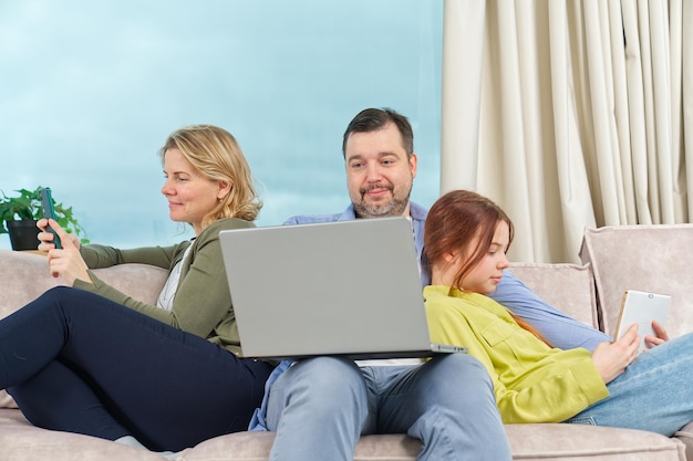 Szczęśliwa rodzina na kanapie za pomocą gadżetu Odpoczynek w domu Korzystanie z urządzeń cyfrowych w domu
