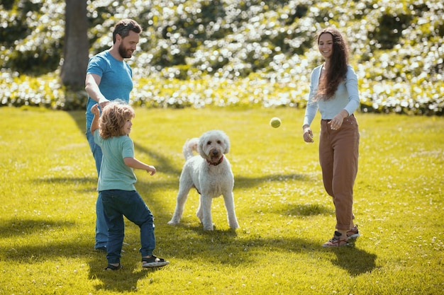Szczęśliwa rodzina na letnim spacerze ojciec matka i dziecko z psem spacerującym po parku i cieszącym się be