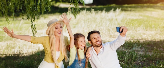 Szczęśliwa rodzina na pikniku robiąca selfie spędzając dzień razem na świeżym powietrzu