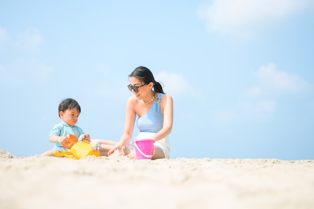 Szczęśliwa rodzina odpoczywa na plaży latem, stopy matki i dziecka w morskiej pianie w wodzie słonecznej w ruchu