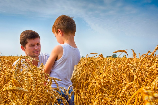 Szczęśliwa rodzina Ojciec i syn na polu pszenicy Mężczyzna pokazuje chłopcu kłos pszenicy