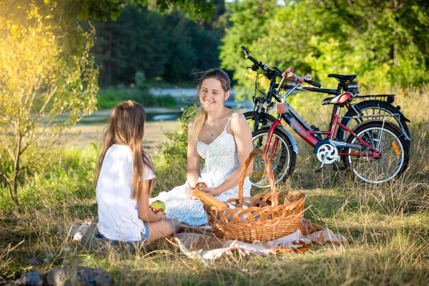 Szczęśliwa rodzina pikniku nad rzeką. Uśmiechnięta matka i córka patrzą na siebie