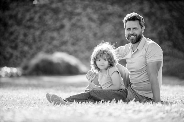 Szczęśliwa rodzina portret ojca i syna chłopca zrelaksować się w letnim parku zielona trawa rodzinna miłość