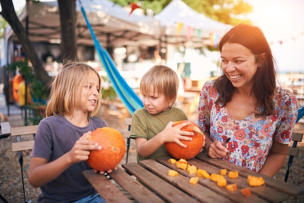 Szczęśliwa rodzina przygotowuje się do Halloween Matka i dwaj synowie rzeźbią dynię