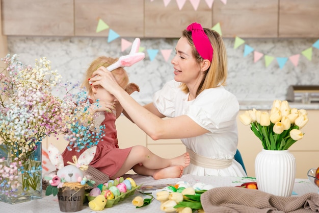 Zdjęcie szczęśliwa rodzina przygotowuje się do wielkanocy śliczna dziewczyna z matką aktywność w domu pojęcie jedności i miłości mama i córka