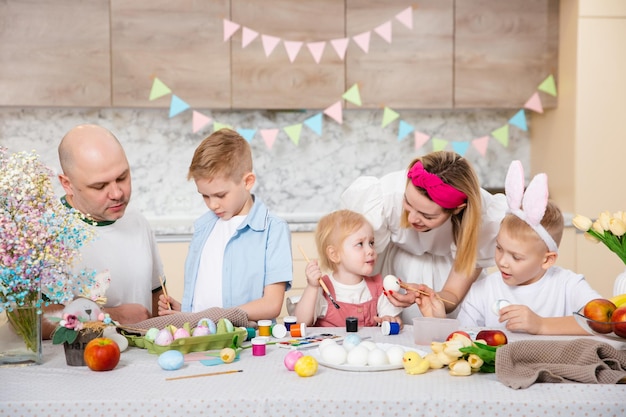 Szczęśliwa rodzina przygotowuje się do Wielkanocy Słodkie dzieci malują jajka Aktywność domowa Pojęcie jedności i miłości Mama tata syn córka Bracia i siostra