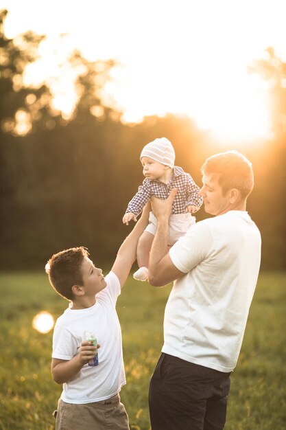 Szczęśliwa rodzina przytulająca się i obejmująca na letnim spacerze Ojciec i jego dwaj synowie spacerują po parku i cieszą się piękną przyrodą Uroczy portret rodzinny