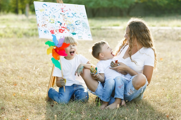 Szczęśliwa rodzina rysunek na zewnątrz. Młoda matka zabawy z małymi dziećmi