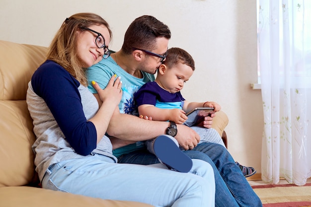 Szczęśliwa rodzina siedzi z tabletem w pokoju na kanapie