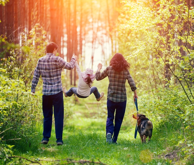 Szczęśliwa rodzina spacerująca z psem po lesie