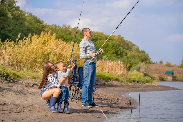 Szczęśliwa rodzina spędza razem czas; uczą syna, aby łowić ryby.