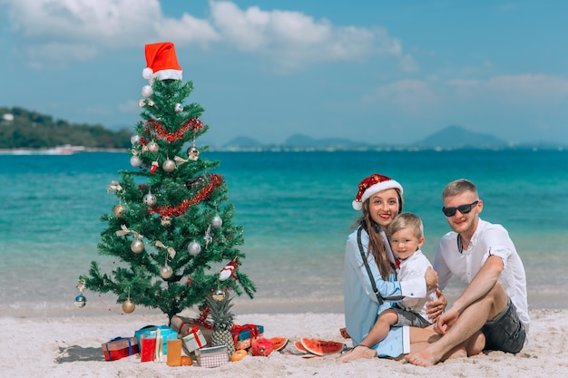 Szczęśliwa rodzina w Boże Narodzenie kapelusze, zabawy na białej plaży