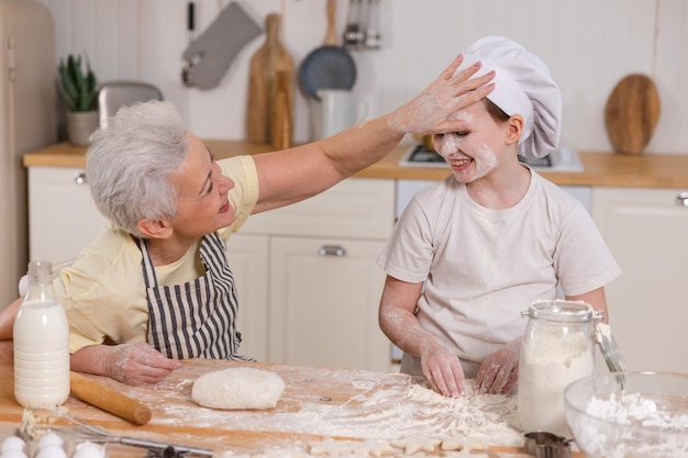 Szczęśliwa rodzina w kuchennej babci i wnuczce dziecko gotuje w kuchni razem babcia ucząc