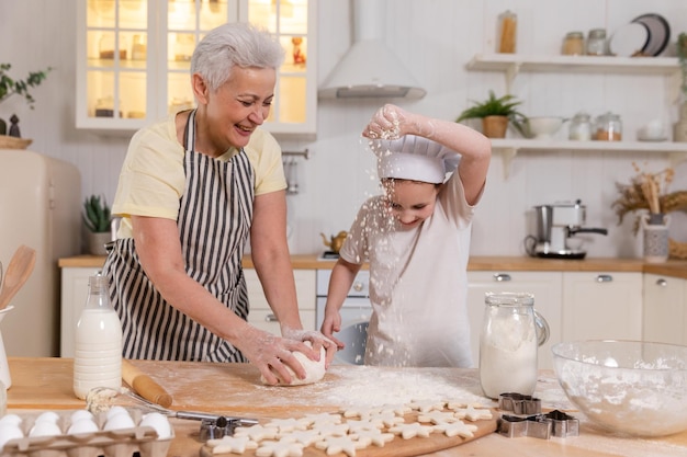 Szczęśliwa rodzina w kuchni Babcia i wnuczka dziecko gotują razem w kuchni Babcia uczy dziecko dziewczynka zagniata ciasto piec ciasteczka Praca zespołowa w gospodarstwie domowym pomaga koncepcja pokoleń rodziny