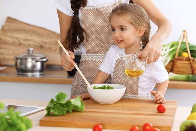 Szczęśliwa Rodzina W Kuchni Córka Mama I Dziecko Gotują Smaczne śniadanie Ze świeżej Sałatki Mały Pomocnik Kroi I Miesza Pomidory Z Zielenią