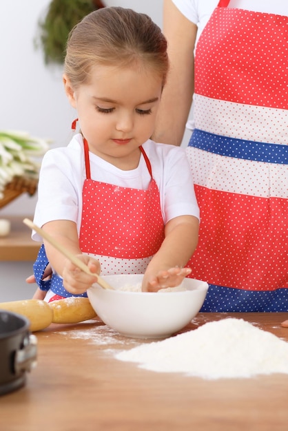 Zdjęcie szczęśliwa rodzina w kuchni córka mama i dziecko gotują świąteczne ciasto lub ciasteczka na dzień matki