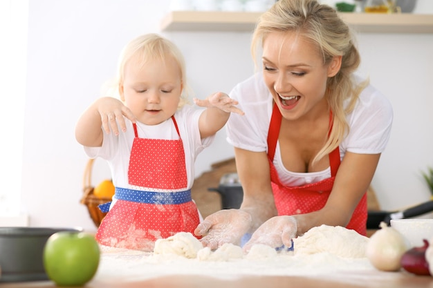 Szczęśliwa rodzina w kuchni. Córka matki i dziecka gotuje świąteczne ciasto lub ciasteczka na dzień matki, nieformalna seria zdjęć stylu życia w prawdziwym wnętrzu