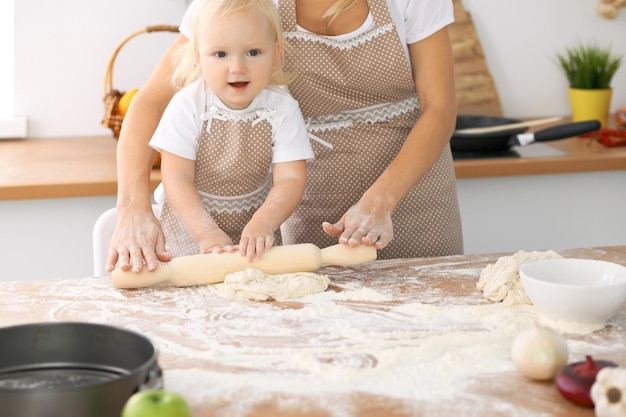 Szczęśliwa rodzina w kuchni. Córka matki i dziecka gotuje świąteczne ciasto lub ciasteczka na dzień matki, nieformalna seria zdjęć stylu życia w prawdziwym wnętrzu