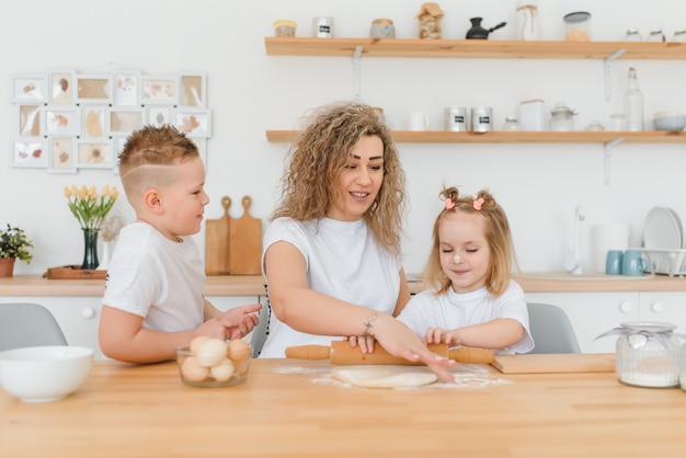 Szczęśliwa rodzina w kuchni. mama i dzieci przygotowują ciasto, pieczą ciasteczka