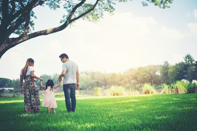 Szczęśliwa rodzina w parku, ojciec i matka bawić się z córką, relaksujemy rodzinnego czas