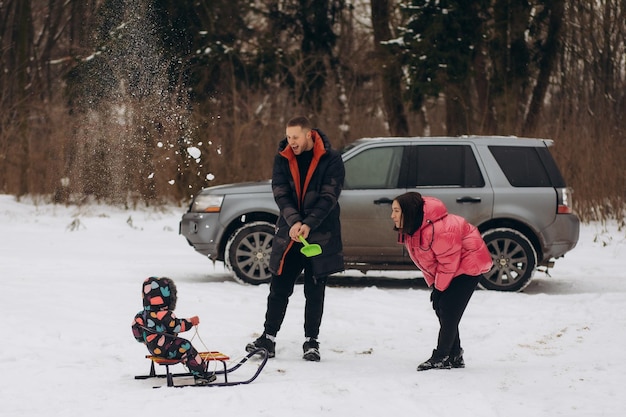 Szczęśliwa rodzina w pobliżu samochodu w lesie w zimowy dzień