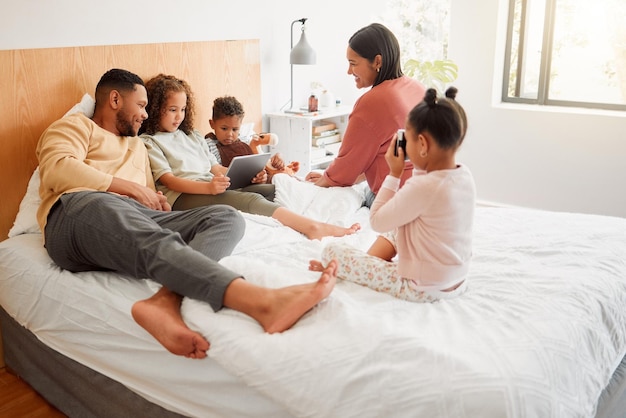 Szczęśliwa rodzina w sypialni, gdy mama i tata bawią się, uśmiechają się i relaksują ze swoimi dziećmi Brat i siostry siedzą razem z mamą i tatą Latynoskie rodzeństwo odpoczywa z rodzicami