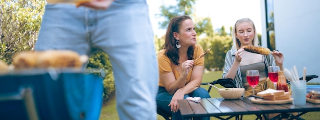 Szczęśliwa rodzina wiwatująca z kolacją grillową na świeżym powietrzu Grupa ludzi bawiąca się podczas weekendowego posiłku BBQ Smak jedzenia i koncepcja lata Mężczyzna gotuje mięso na grillu na letnim przyjęciu