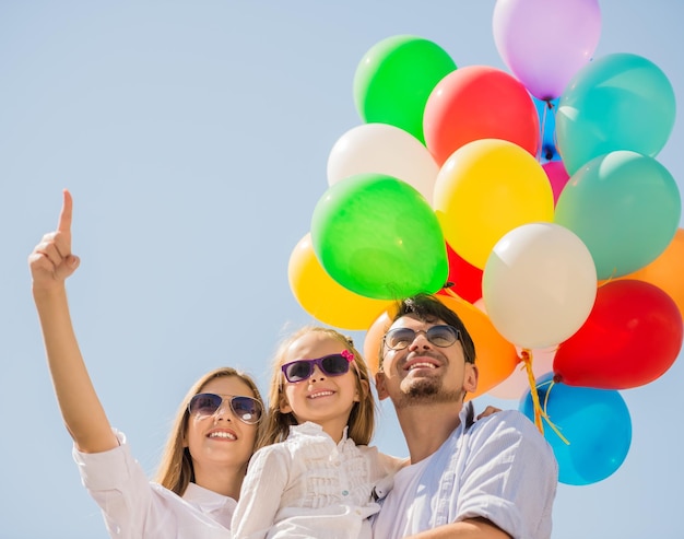 Szczęśliwa rodzina z balonami patrzącymi na zewnątrz w letni dzień mama wskazująca na górę