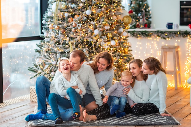 Szczęśliwa rodzina z czwórką rodzeństwa przy choince z prezentami. Świąteczny poranek rodzinny, koncepcja świątecznego nastroju