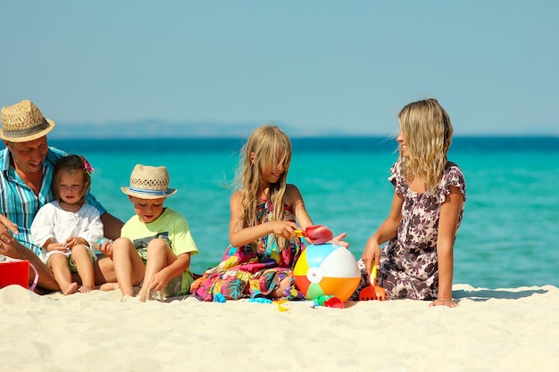 Szczęśliwa rodzina z dziećmi bawi się na plaży w Grecji podczas letnich wakacji