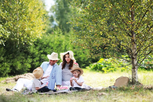 Zdjęcie szczęśliwa rodzina z dziećmi na pikniku w parku, rodzice z dziećmi siedzą na trawie w ogrodzie i jedzą arbuza na świeżym powietrzu