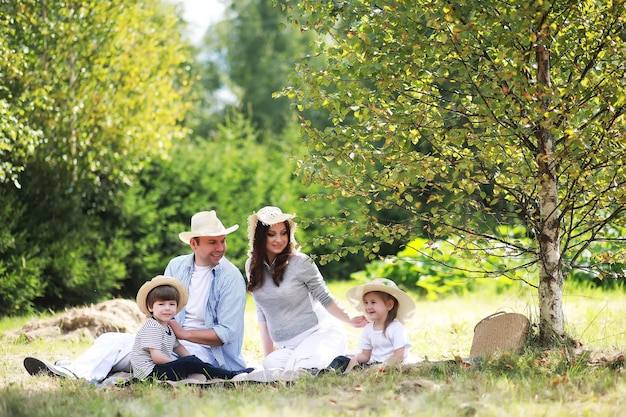 Szczęśliwa rodzina z dziećmi na pikniku w parku, rodzice z dziećmi siedzą na trawie w ogrodzie i jedzą arbuza na świeżym powietrzu