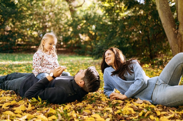 Szczęśliwa rodzina z małą córeczką w jesiennym parku rekreacji na świeżym powietrzu