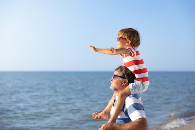 Szczęśliwa rodzina zabawy na plaży Dziadek i chłopiec na tle błękitnego morza i nieba Letnie wakacje i koncepcja dzień ojca