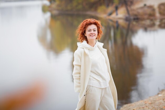 Szczęśliwa rudowłosa kobieta w białych ubraniach