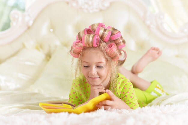 Szczęśliwa śliczna mała dziewczynka w lokówki z książką