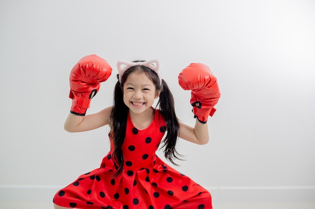 Szczęśliwa śmieszna mała dziewczynka z czerwonymi bokserskimi rękawiczkami odizolowywającymi