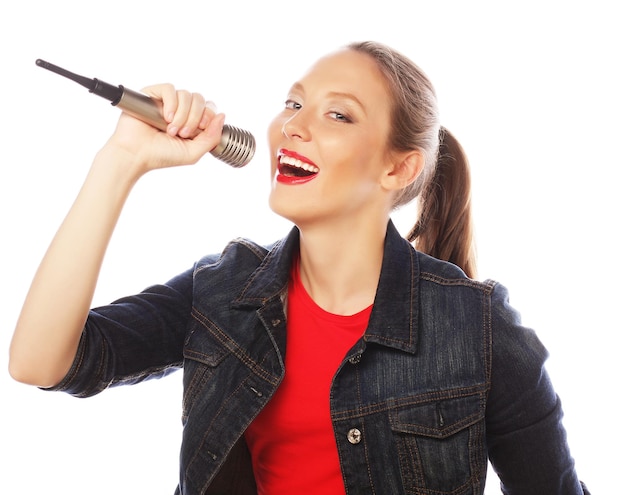 Szczęśliwa śpiewająca dziewczyna Piękna kobieta ubrana w czerwoną koszulkę z mikrofonem na białym tle