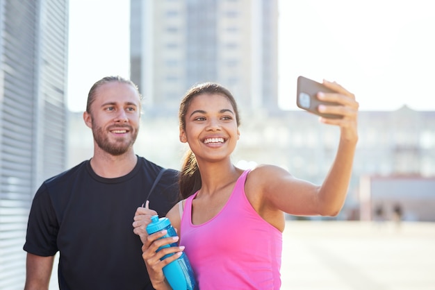 Szczęśliwa sportive dziewczyna biorąca selfie ze sportowcem