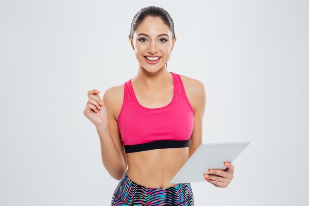 Szczęśliwa sportowa kobieta korzystająca z komputera typu tablet