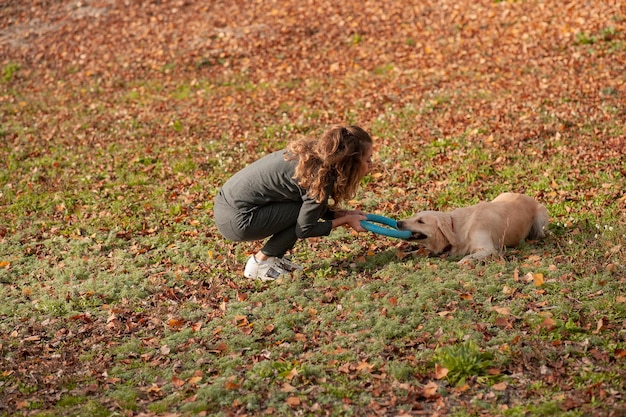 Szczęśliwa sportowa kobieta odpoczywa ze swoim psem golden retriever Lekkoatletka cieszy się świeżym powietrzem ze swoim zwierzakiem Kobieta trenuje na zewnątrz jesienią