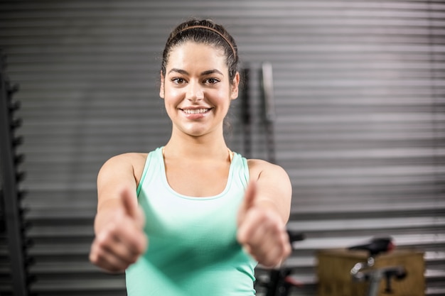 Szczęśliwa sportowa kobieta z aprobatami przy gym