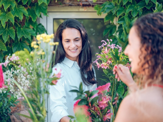 Szczęśliwa sprzedawczyni pokazująca bukiety kwiatów szczęśliwemu klientowi podczas pracy w ogrodzie latem