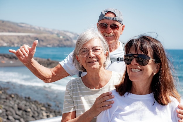 Szczęśliwa starsza grupa podróżników cieszących się wakacjami na plaży w słoneczny dzień uśmiechając się szczęśliwie