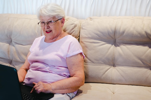 Szczęśliwa starsza kobieta korzysta z laptopa w domu Starsza dojrzała starsza kobieta ogląda szkolenie biznesowe