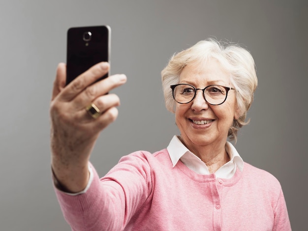 Szczęśliwa starsza kobieta robi selfie swoim smartfonem