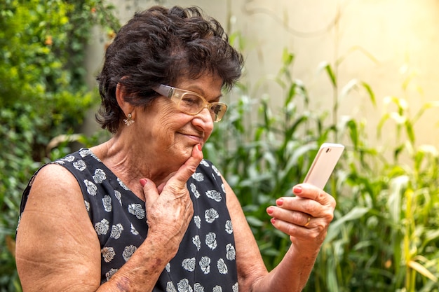 Szczęśliwa starsza kobieta używa telefon komórkowego