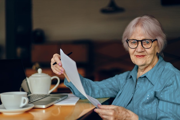 Szczęśliwa starsza kobieta w kawiarni filiżanka napoju laptop sieci społecznościowe niezmienione